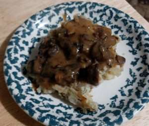 Fall Mushroom Hunting with brown mushroom gravy over white potatoes on a green and white plate
