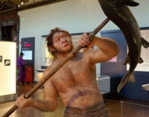 Photo of a statue of a Homo erectus man spearing a large fish for article on plant blindness